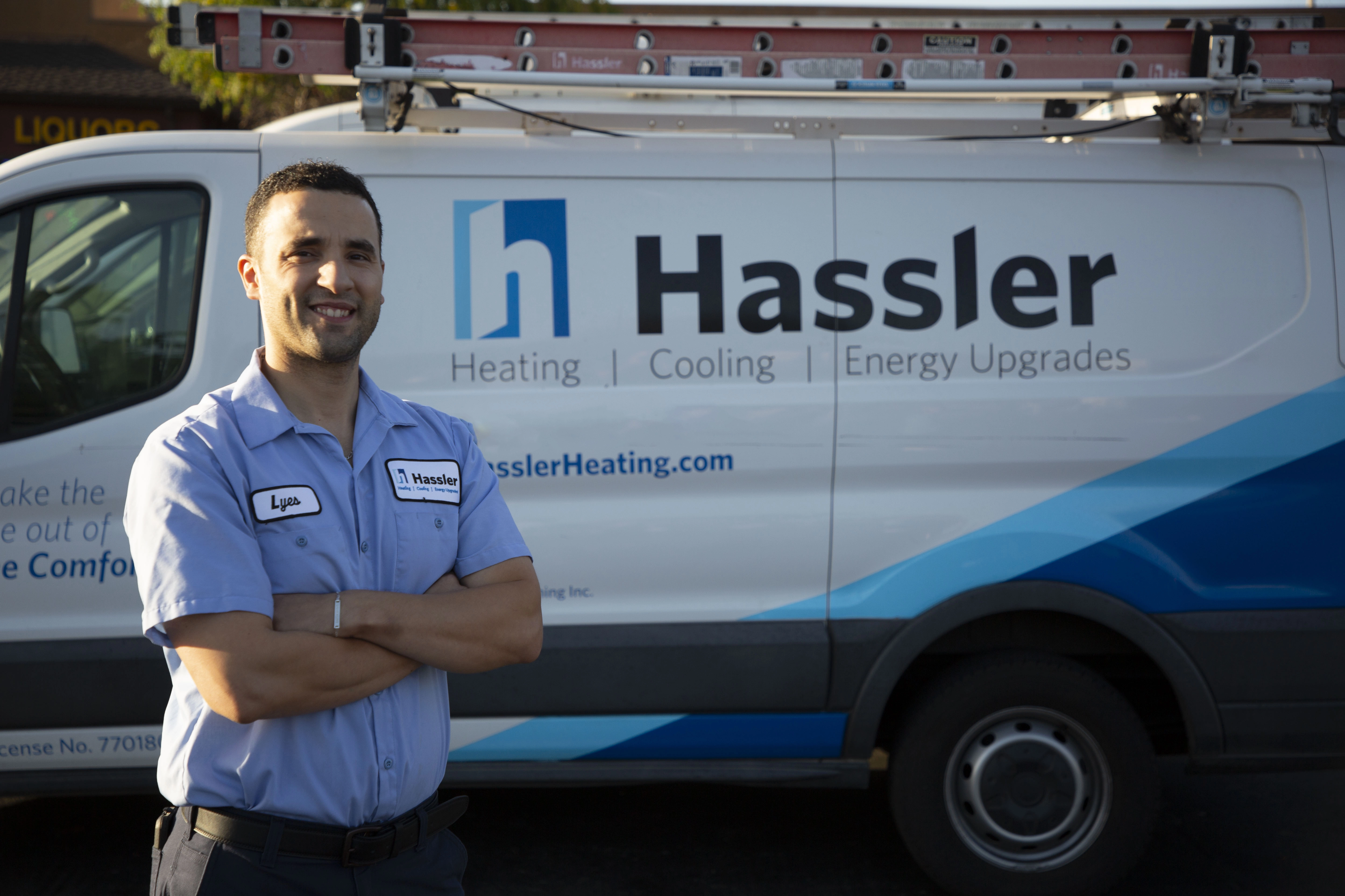 Picture of A Hassler technician poses next to one of the company's service trucks. - Hassler Heating & Air Conditioning, LLC