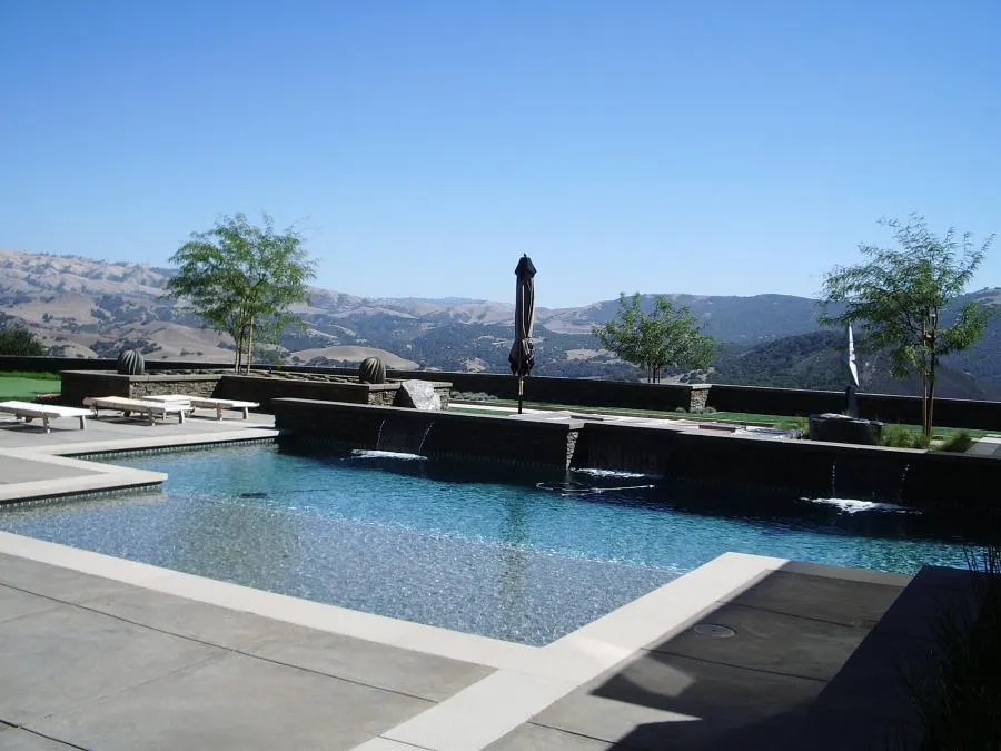 Picture of A shallow beach pool entry combined with deeper swim lanes and decorative spillways - Jerry Allison Landscaping, Inc.