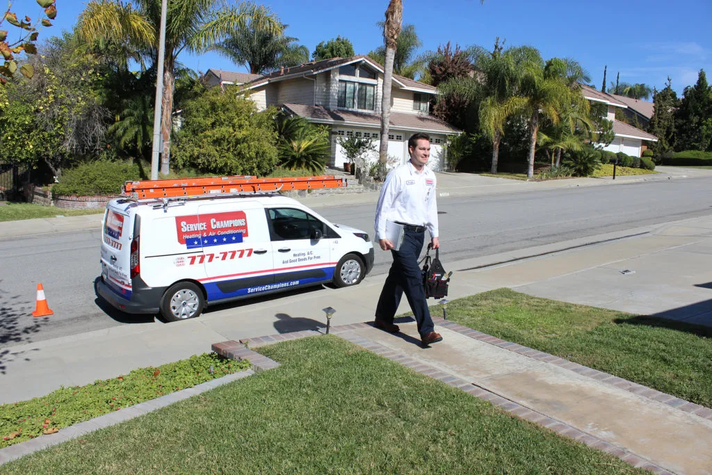 Picture of A Service Champions Plumbing Heating & AC technician arrives at a client's home to work on an HVAC system. - Service Champions Plumbing, Heating & AC