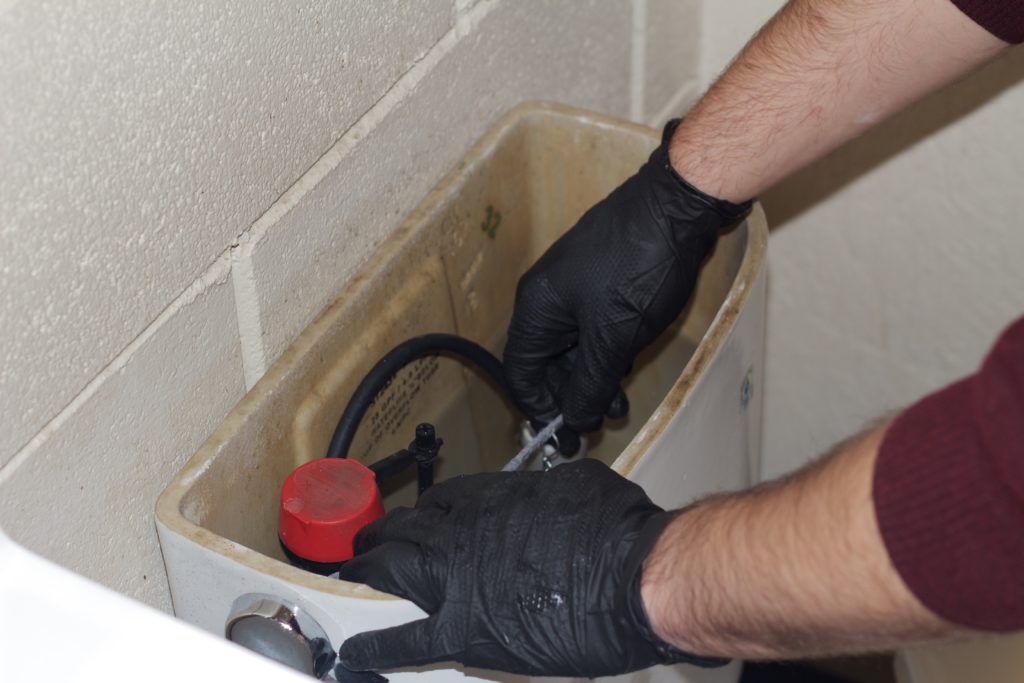 Picture of A Shepherd’s Plumbing Heating & Air Conditioning, Inc. technician repairs a customer’s toilet. - Shepherd's Plumbing Heating and Air Conditioning, Inc.