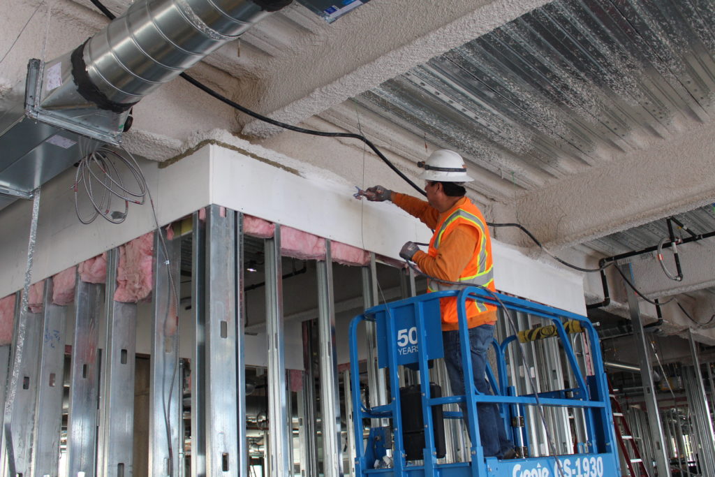 Picture of An Alcal Specialty Contracting employee installs fireproofing spray on a commercial building. - Alcal Specialty Contracting, Inc.