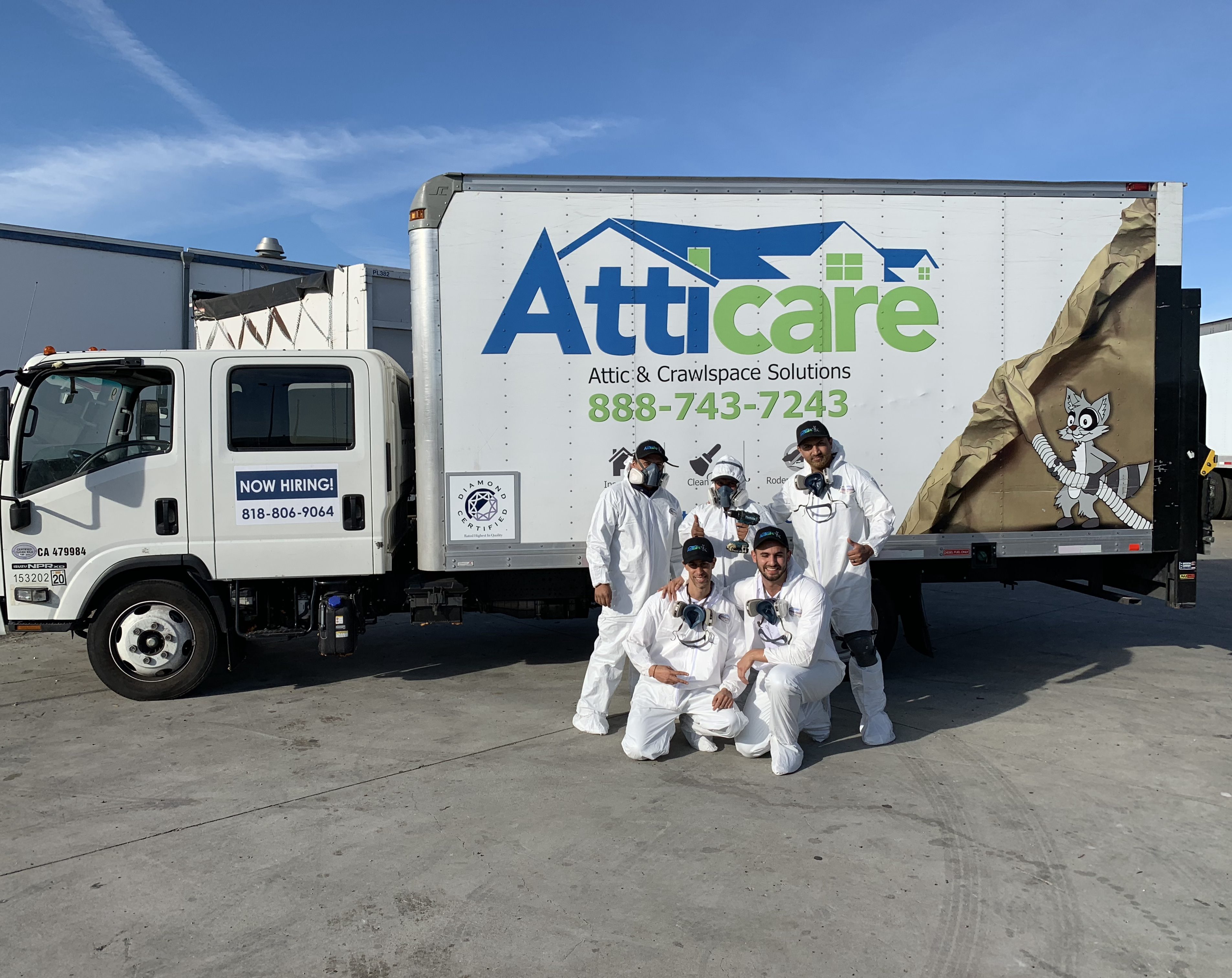 Picture of Atticare team members pose in front of one of the company's service trucks. - Atticare Construction