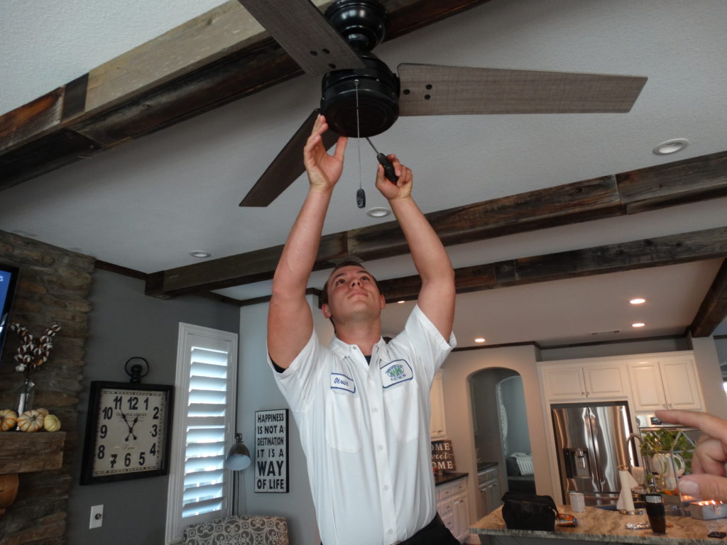 Picture of A Maine Electric Inc. technician works on a customer's ceiling fan. - Service Champions