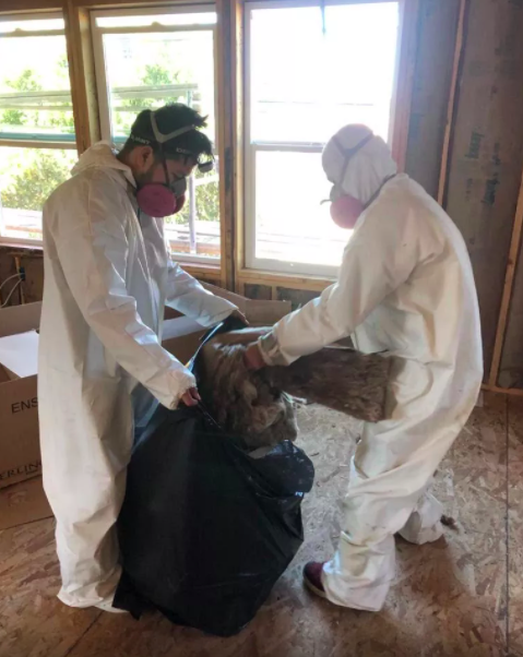 Picture of Two Johnson’s Insulation crew members clean insulation debris after completing a new construction project. - Johnson's Insulation