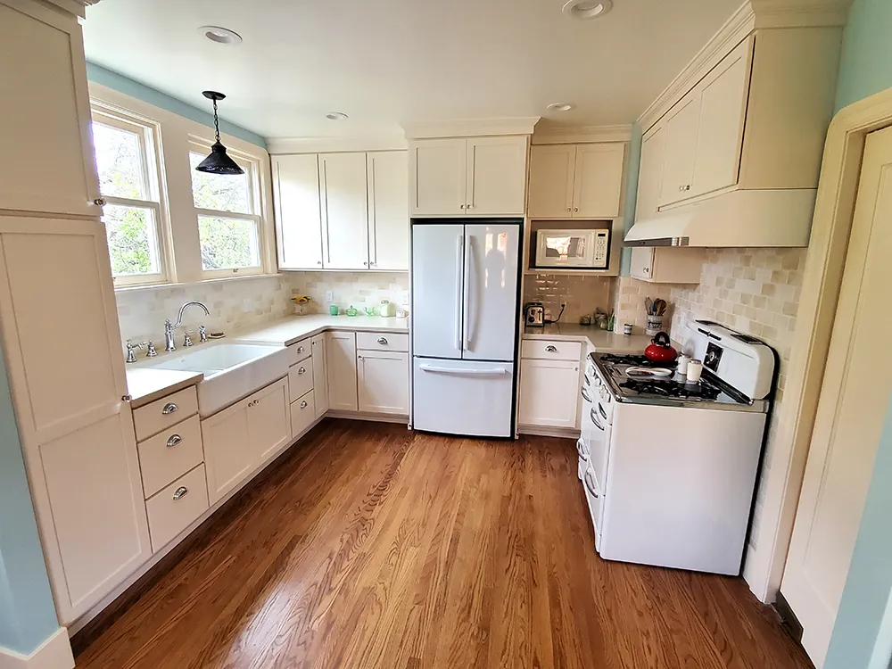 Picture of Cook's Kitchen & Bath opened the wall in this Albany kitchen to make the space seem bigger. The homeowners wanted a classic feel with all-new everything. The cabinetry is a cream-colored shaker style from Huntwood and the farm-style apron sink is from Kohler. The tile backsplash is a subway pattern with a mix of color called the "butter blend" from Melange which sets off the Caesarstone countertop. - Cook's Kitchen & Bath, Inc.