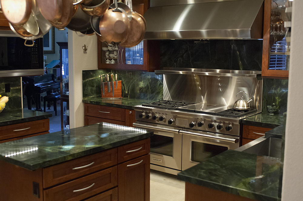 Picture of The centerpiece for this total room transformation is a 60-inch Wolf gas range with a custom vent hood. The next eye-catching aspect of this kitchen is a green Vitoria Regia Granite countertop and bac - Cook's Kitchen & Bath, Inc.