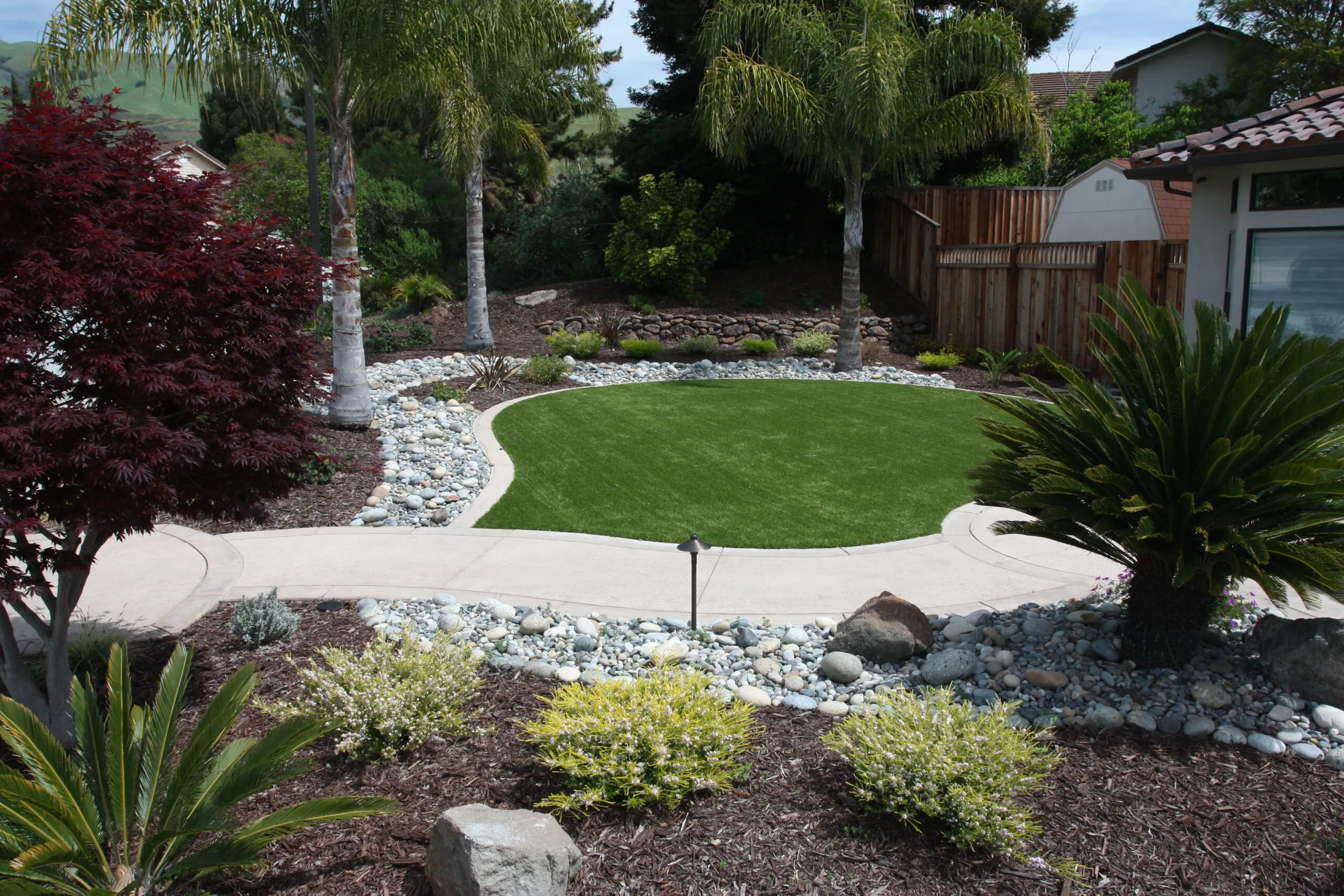 Picture of Koch & Associates installed drought-tolerant plantings cobbles and synthetic turf to provide a water-wise solution for this front yard. - Koch & Associates, Inc.