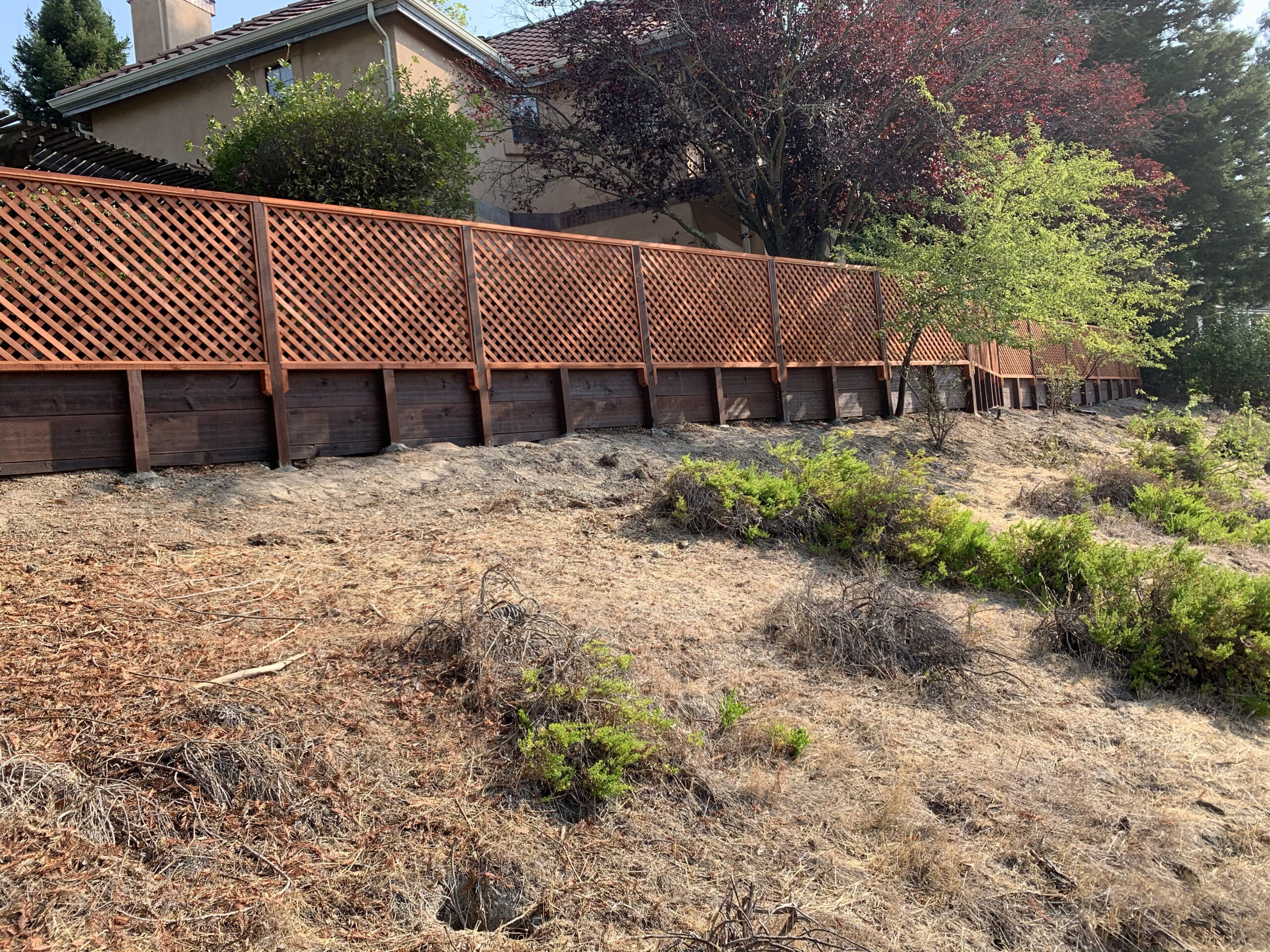 Picture of AMM Fencing built this jumbo-style lattice fence over a client’s retaining wall. - AMM Fencing