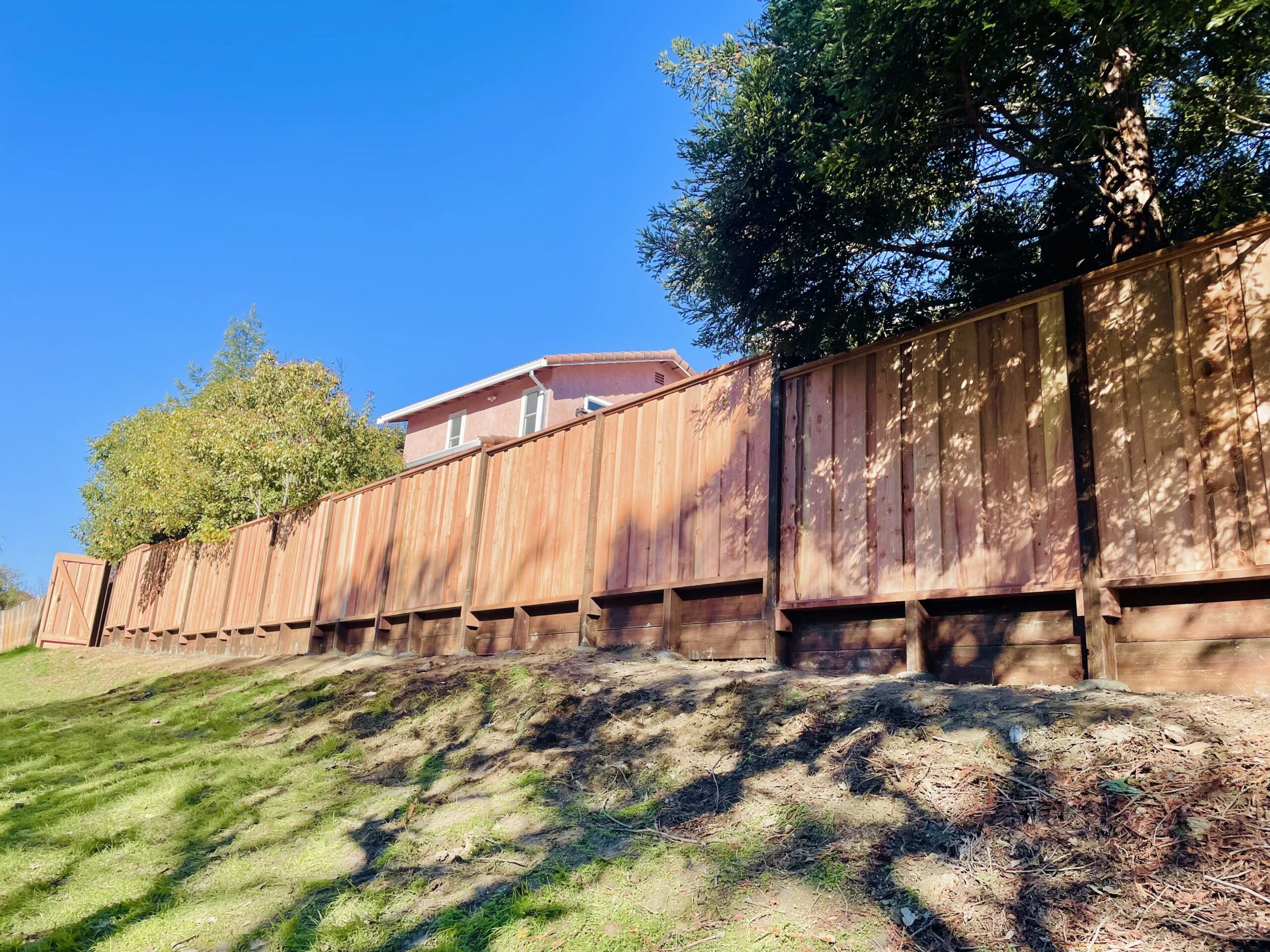 Picture of AMM Fencing installed this retaining wall with a redwood fence. - AMM Fencing