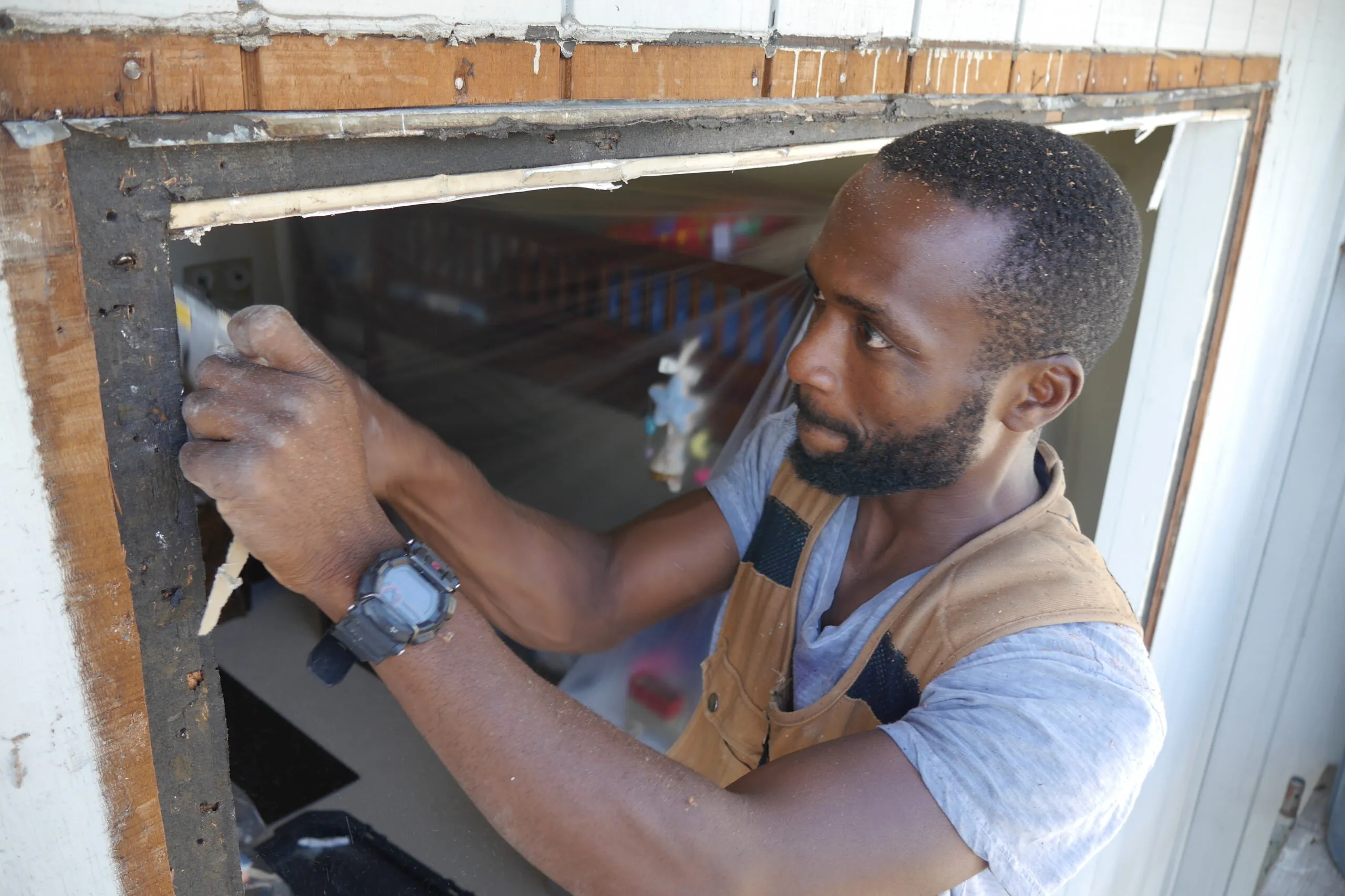 Picture of Master Installer Ahoah cuts away wall board in preparation for a "new construction" installation of a new window. - Save Energy Company