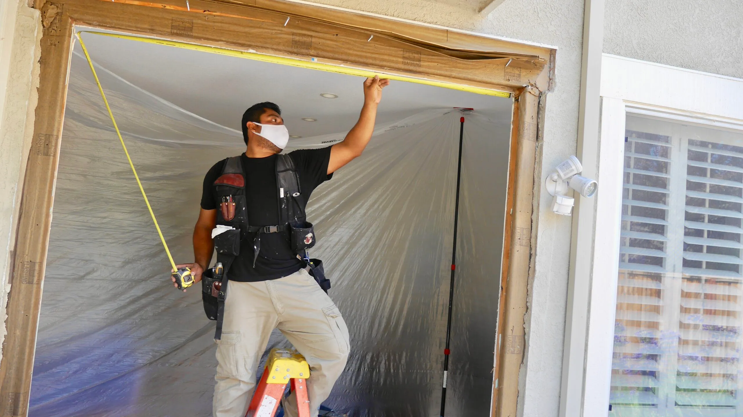 Picture of Master Installer Aldrin carefully checks the measurements of the new opening for a sliding patio door. - Save Energy Company