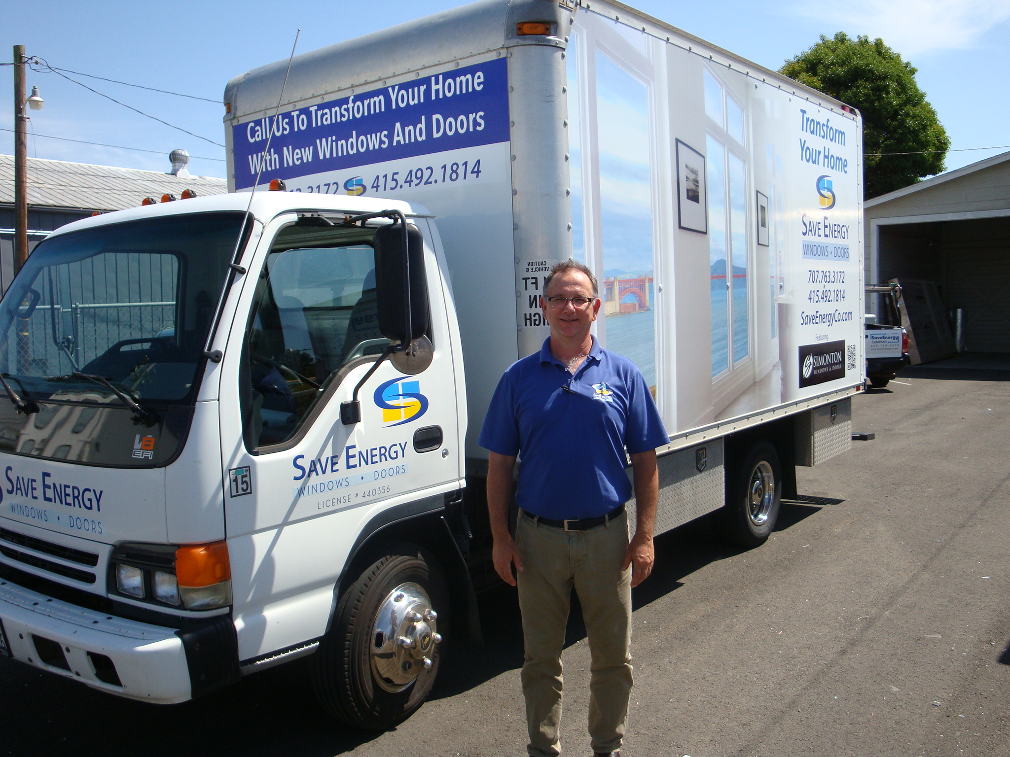 Picture of John Gorman owner and president of Save Energy Company proudly stands next to a newly wrapped production truck. It serves as a mobile billboard for the company as well as an onsite workshop for the in - Save Energy Company